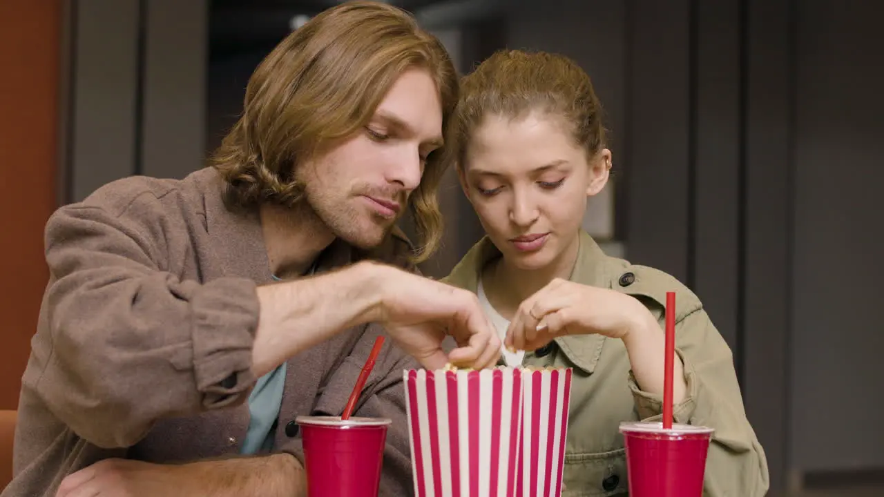 Happy Couple Eating Popcorn While Talking And Laughing Together At The Cinema Snack Bar