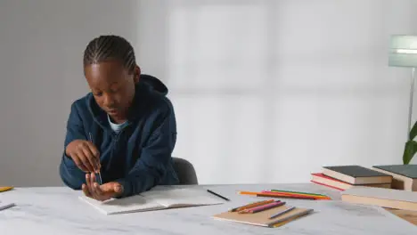 Studio Shot Of Boy At Table Struggling To Concentrate On School Book 3