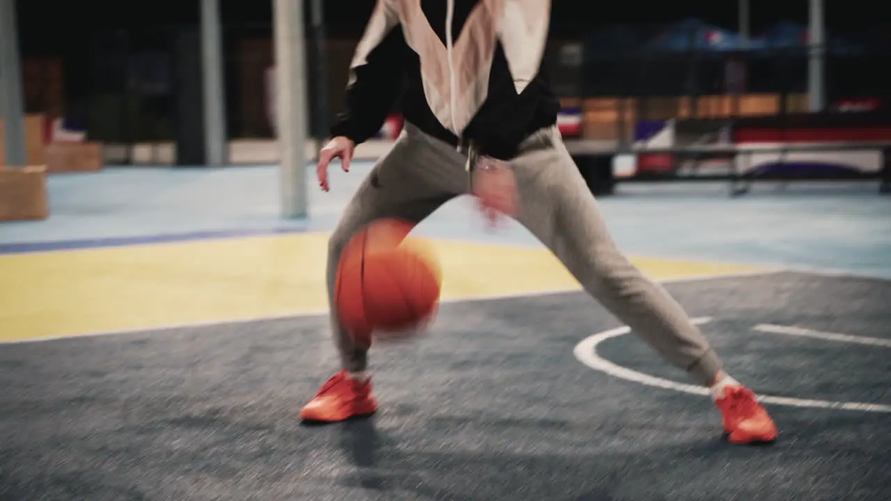 Close Up Of A Female Basketball Player Training And Bouncing The Ball On Outdoor Court At Night