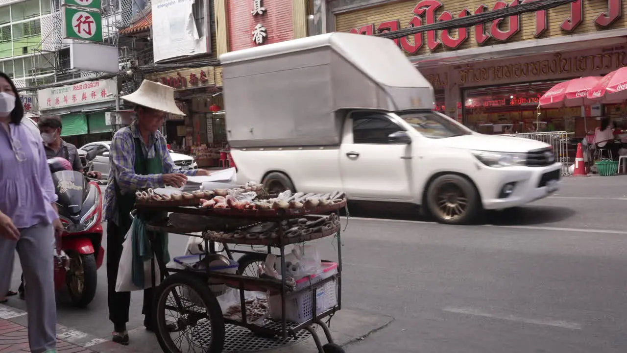 Street Food Vendor with Traditional Hat Selling Food in Chinatown Bangkok Thailand