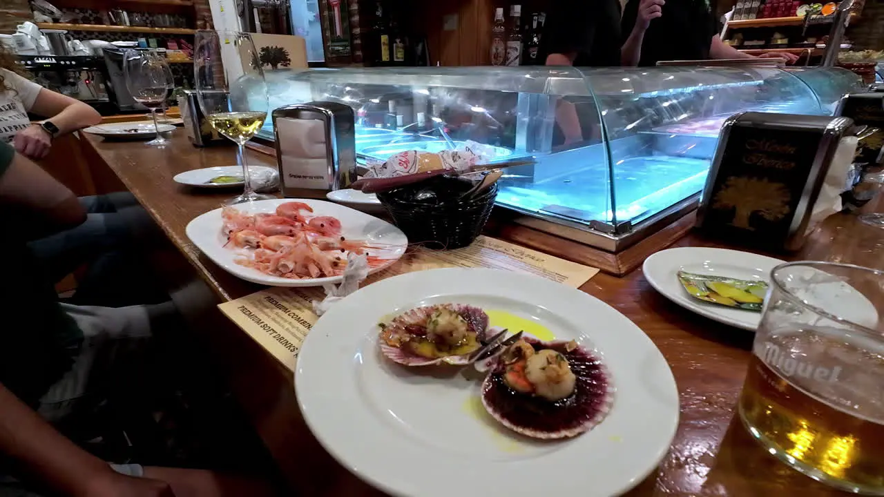 Person enjoying a fresh scallop at a seafood bar in Malaga Spain