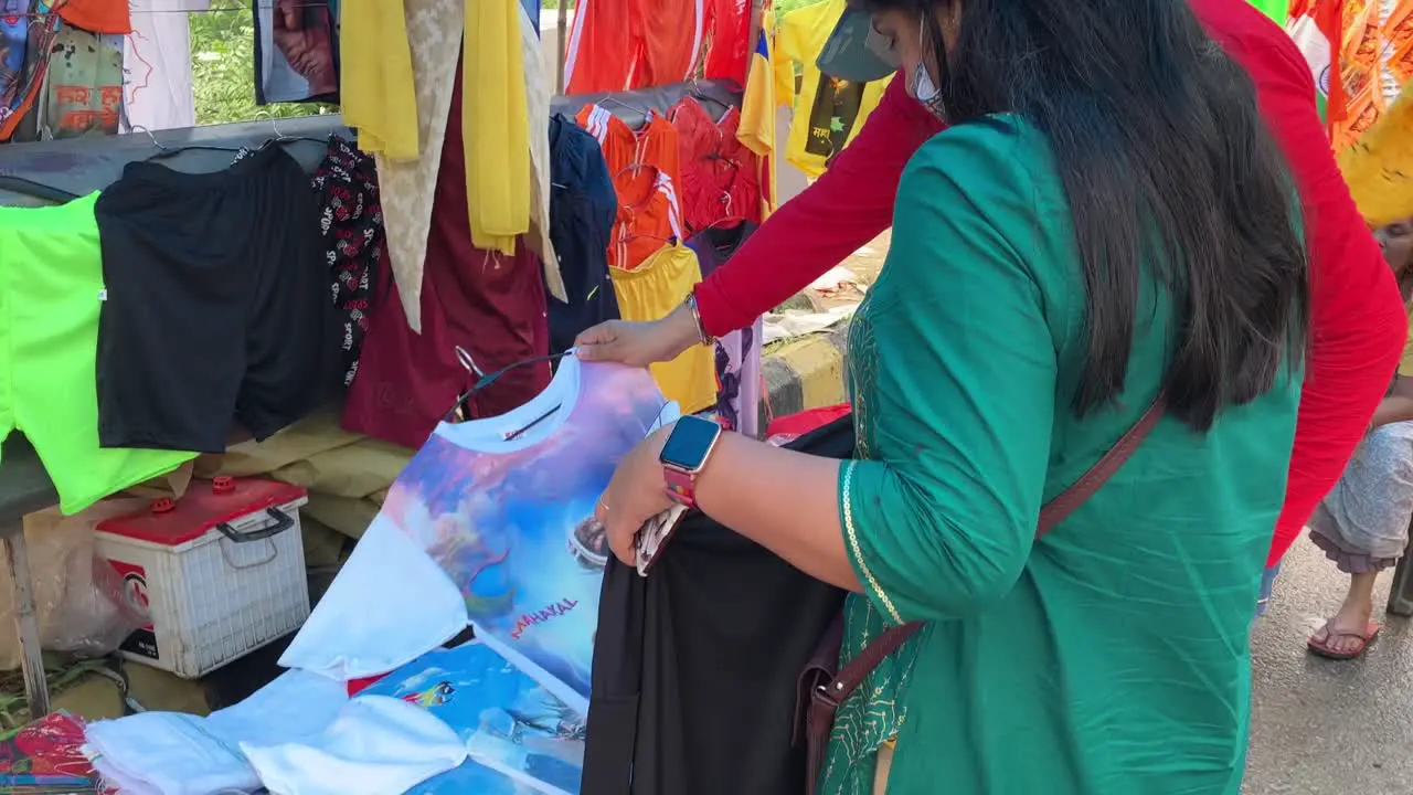 A lady shopkeeper displays clothes with lord shiva prints for sale to pilgrims