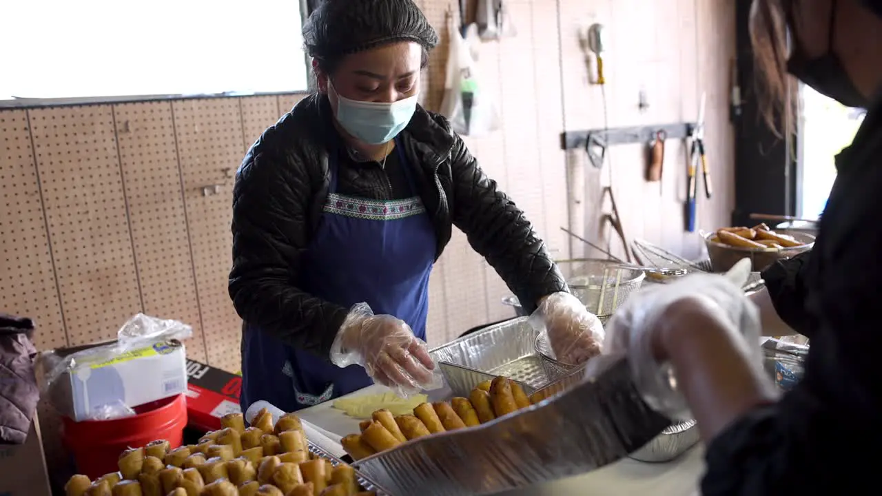 Asian Woman Placing Fresh Egg Rolls In Serving Dish