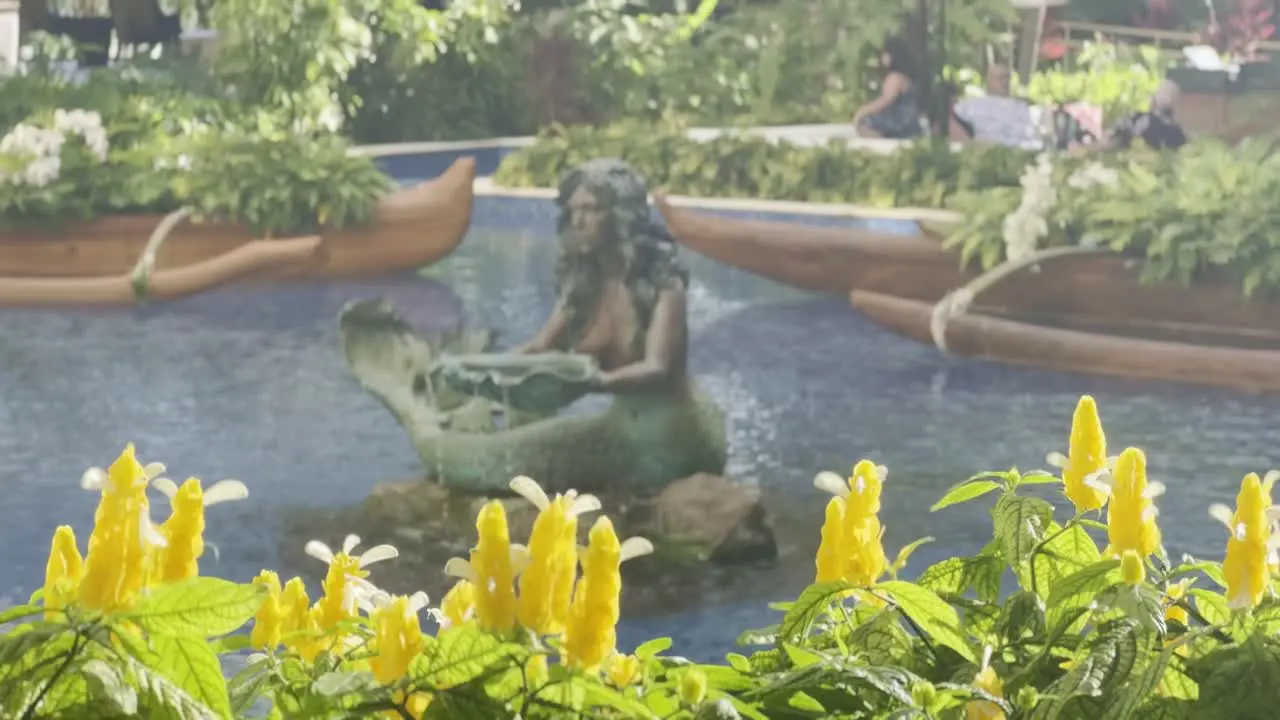 Cinematic panning shot of colorful flowers to a mermaid sculpture in the lobby of the Grand Wailea luxury resort in Maui Hawai'i