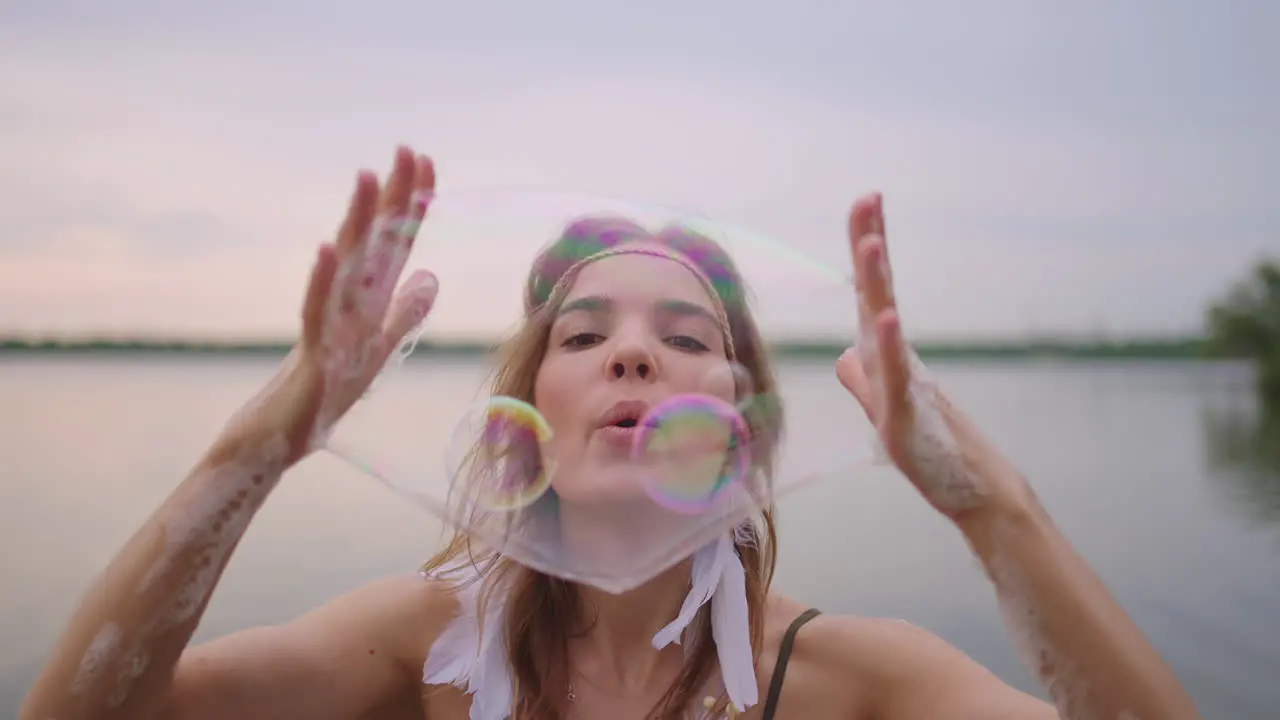 A young girl artist shows magic tricks using soap bubbles Create soap bubbles in your hands and inflate them location theatrical circus show at sunset