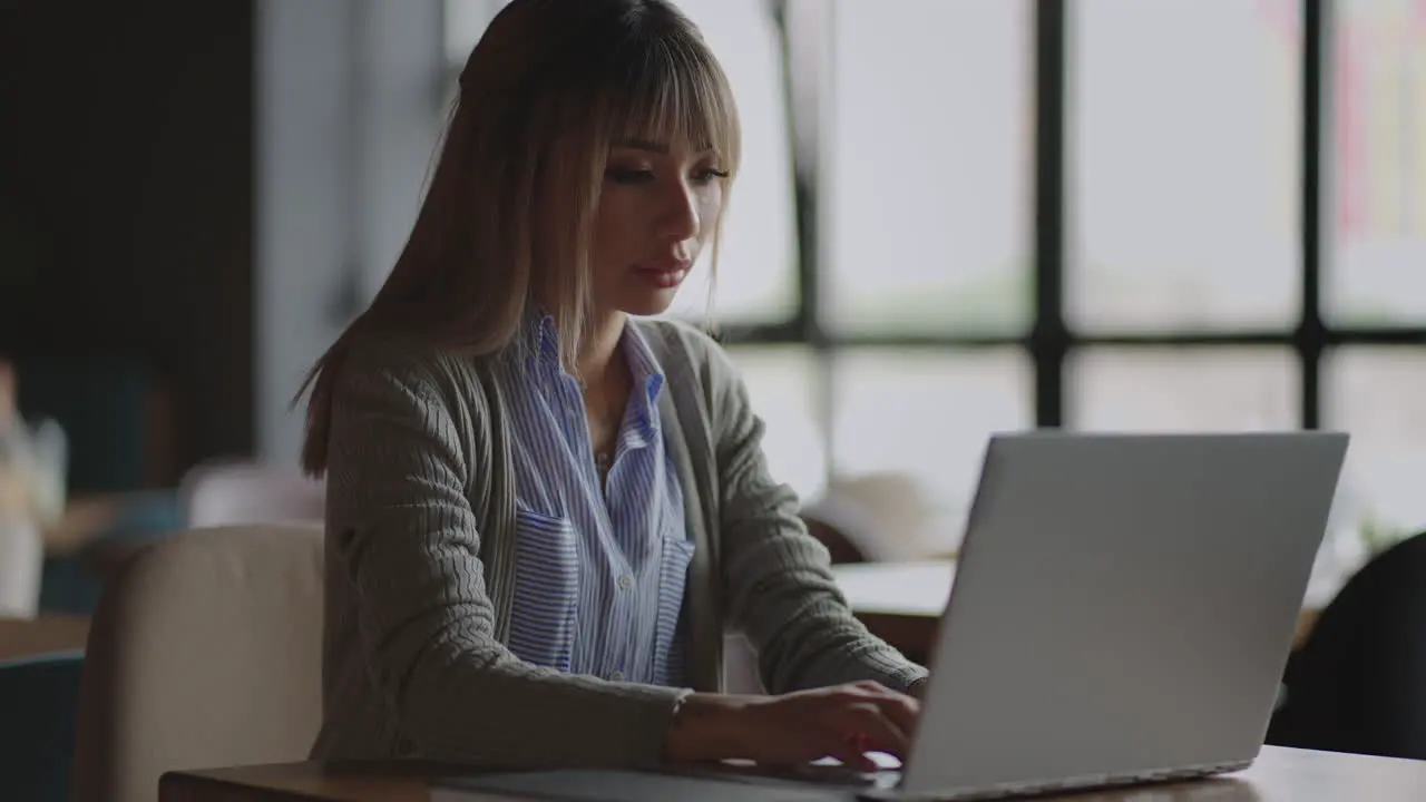 Young Asian attractive female office worker sitting at the laptop computer at the desk working and thinking