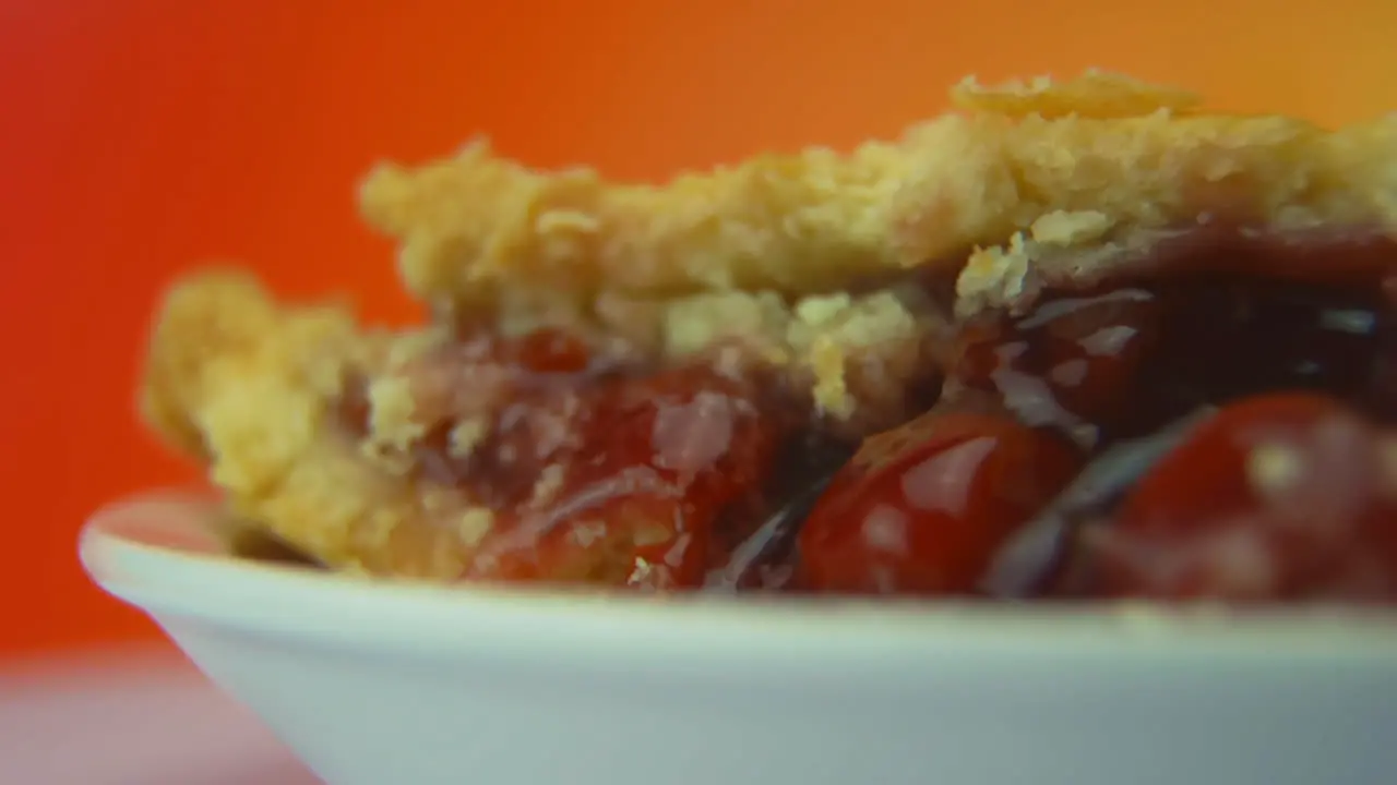 [Camera Used Canon C300] Macro shot low angle rotating cherry pie slice with oozing cherry glaze