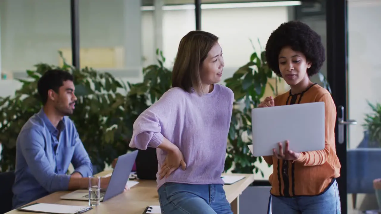 Diverse business people talking using a laptop in modern office