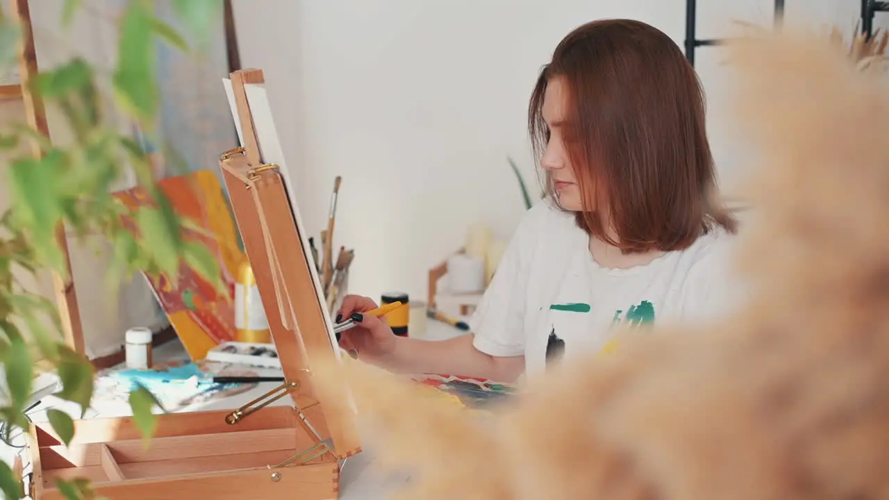 A Red Haired Young Woman Artist Painting A Frame 1