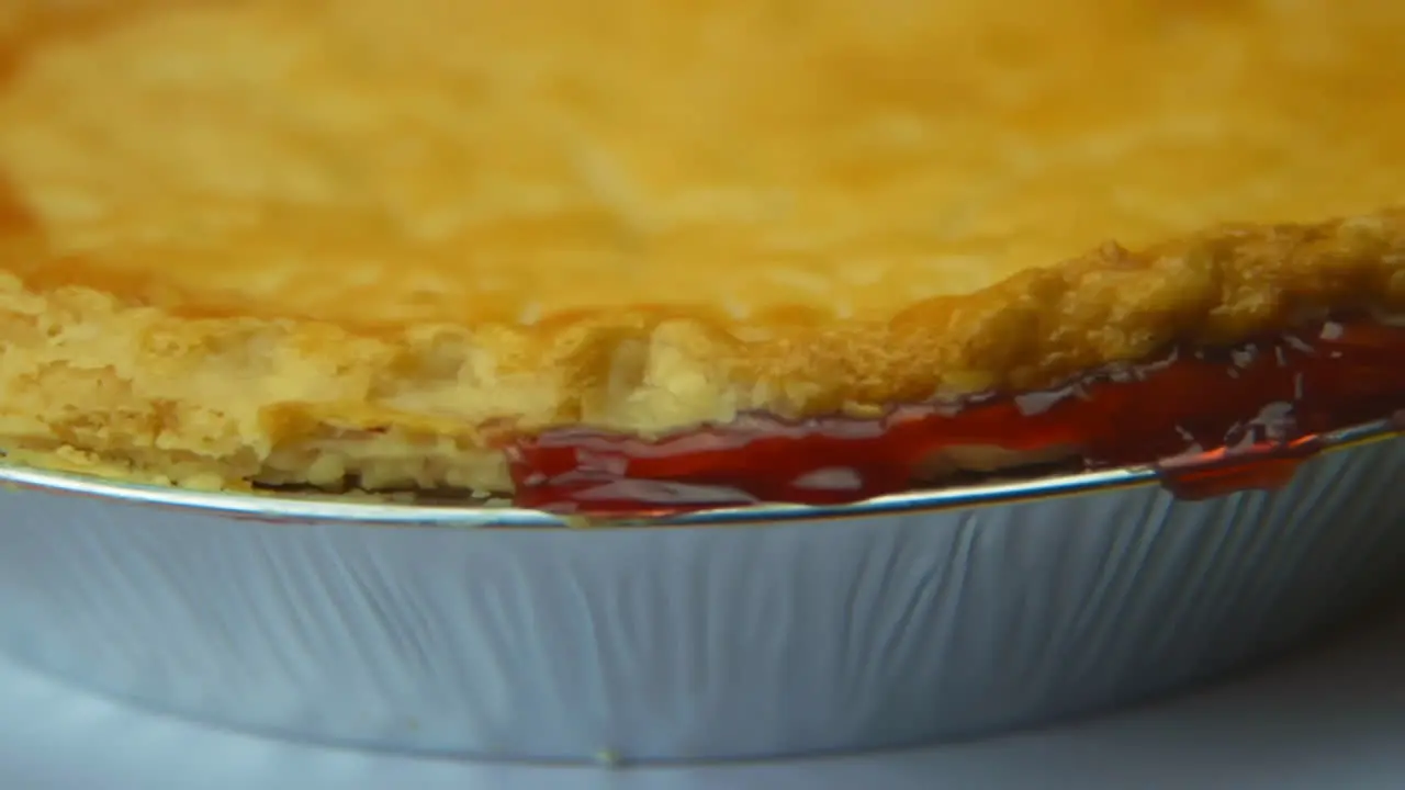 [Camera Used Canon C300] Close-up rotating cherry pie crust with cherry glaze oozing out the sides