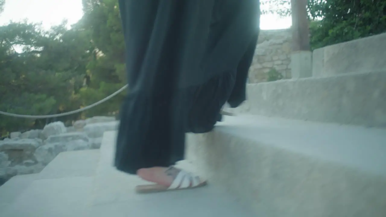 mid shot of person walking up steps in white sandals and dress