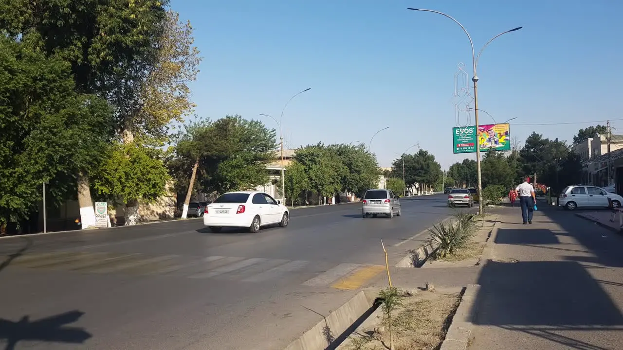 City Street Traffic in Kokand Uzbekistan on Hot Sunny Day Shops People and Cars Panorama