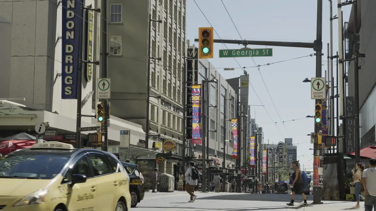 Pedestrians crossing Granville Street corner West Georgia Street in Vancouver on a sunny day handheld static slow motion