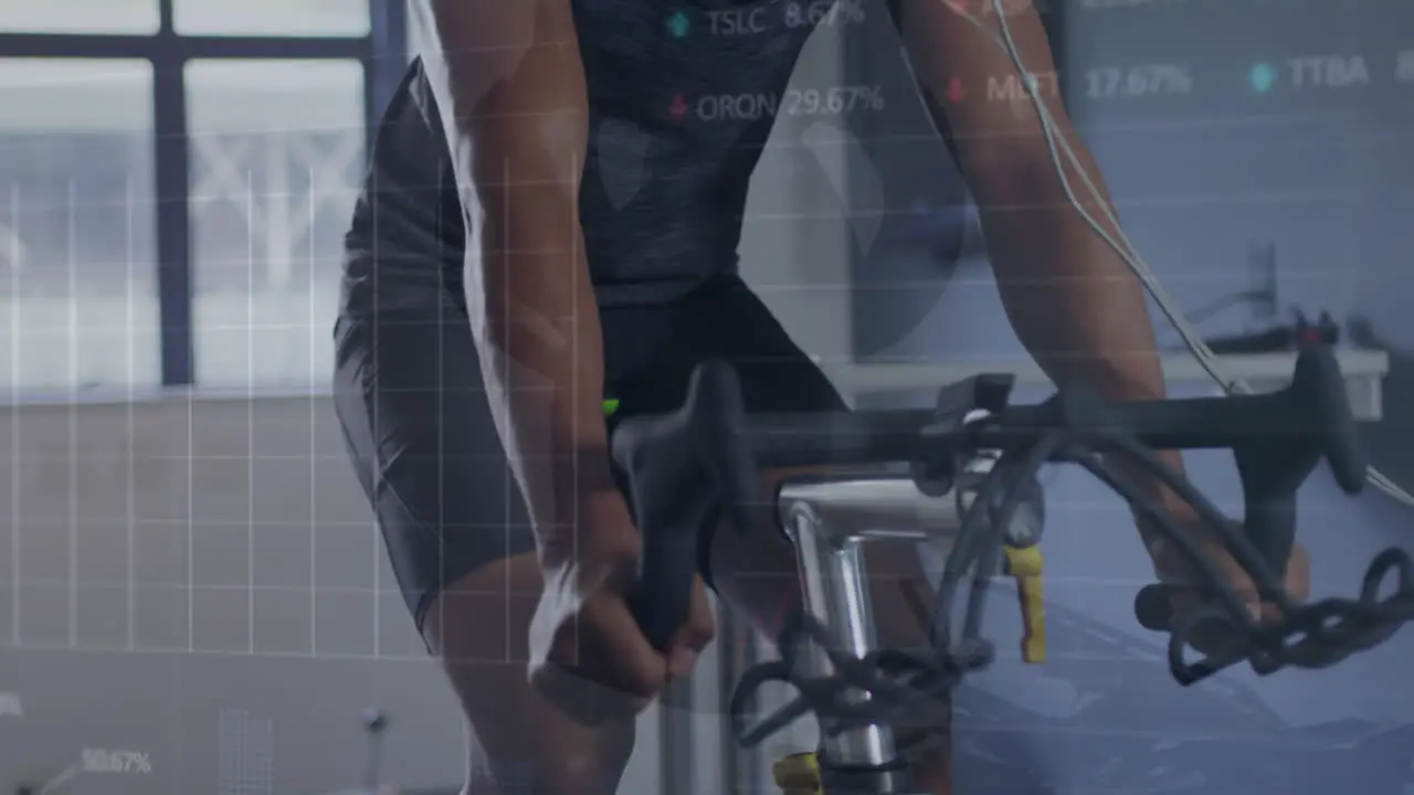 Animation of stock market data processing over biracial fit man training on exercise bike at the gym