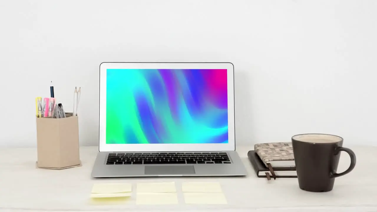 Animation of laptop with colorful moving shapes on screen on desk