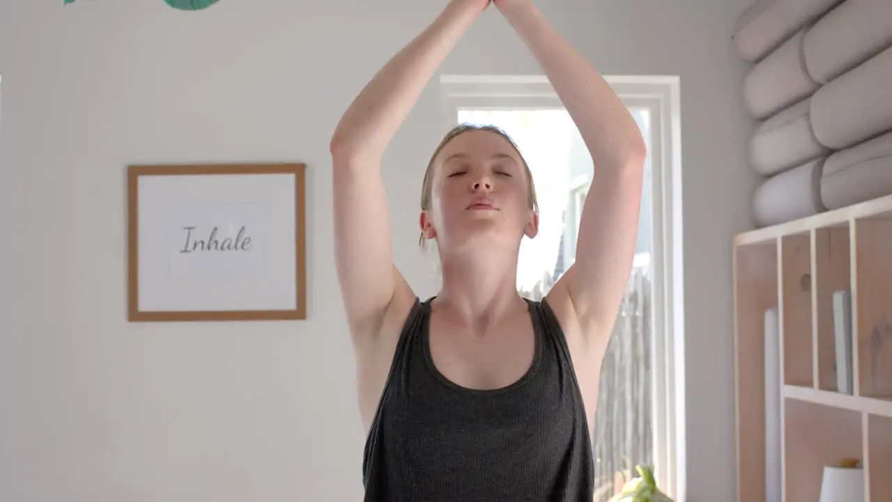 Focused caucasian fitness woman practicing yoga in white room slow motion