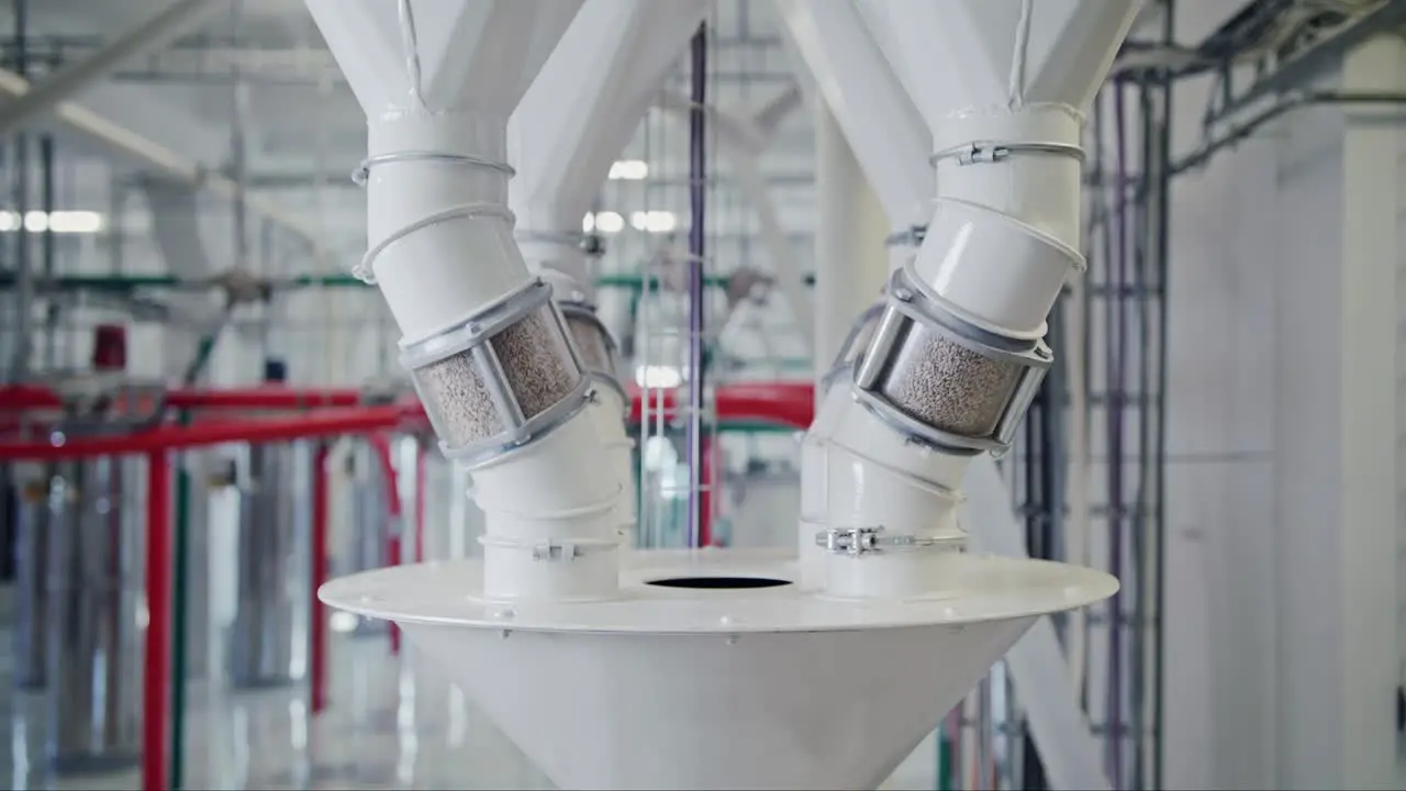 Grain going through transparent inspection tubes at a state-of-the-art grain mill facility showcasing large-scale food production on an industrial level