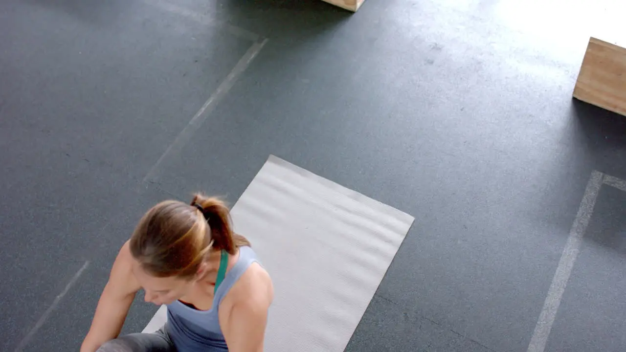 Fit young Caucasian woman exercises on a mat at the gym