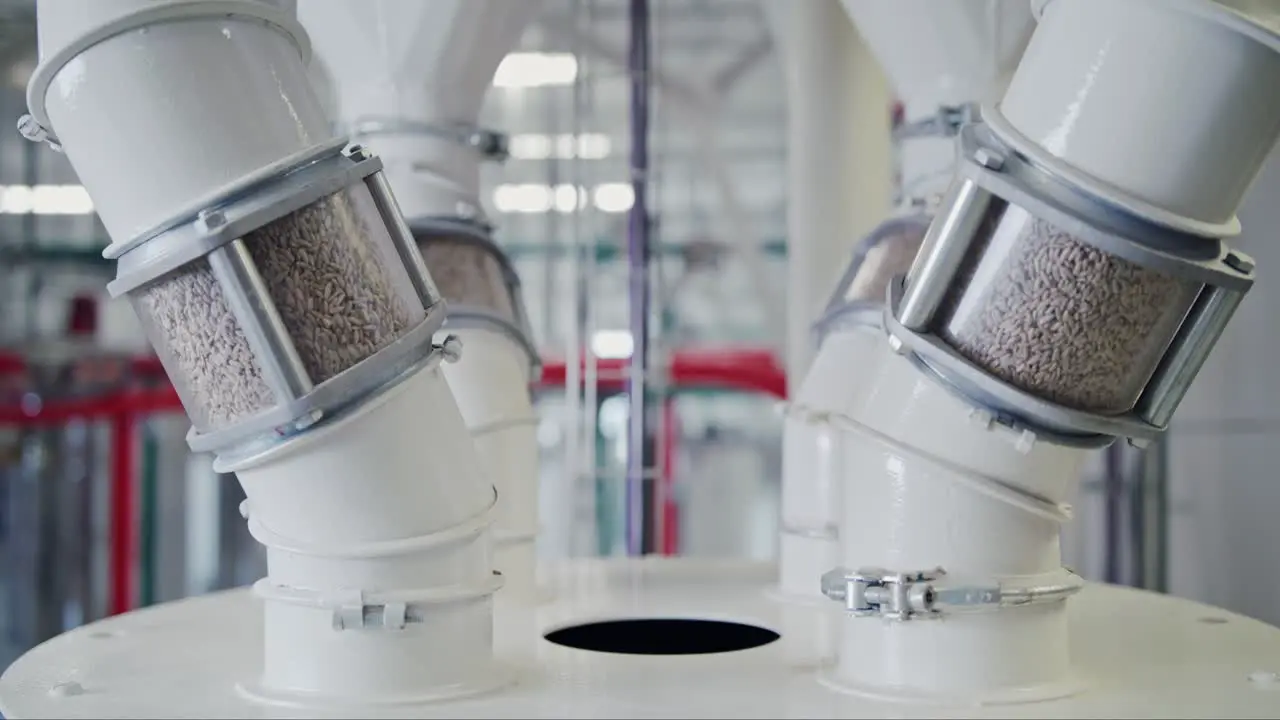 Dolly shot of grain pouring through inspection tubes at a state-of-the-art grain mill facility showcasing large-scale food production on an industrial level