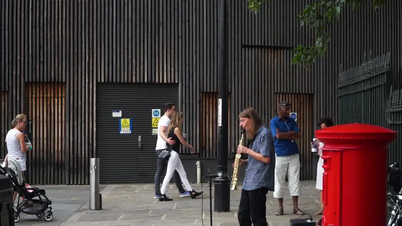 Guy playig saxophone in London street next to famous telephone booth