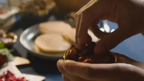 Person Eating Dates At Muslim Family Table At Home Set For Iftar Meal Breaking Daily Fast During Ramadan