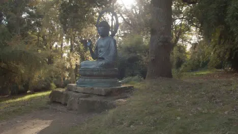 Sculpture Of Buddha In Arboretum With Colourful Autumn Trees In Background