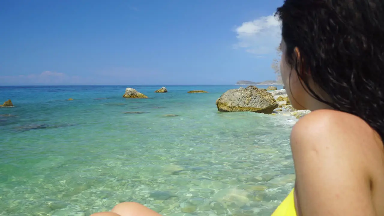 Sea shore with crystal emerald water washing cliffs and girl watching paradise seascape on vacation