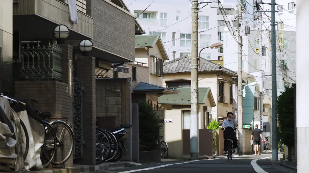 A lone cyclist wearing a mask in Tokyo on a quiet Japanese city street during the pandemic