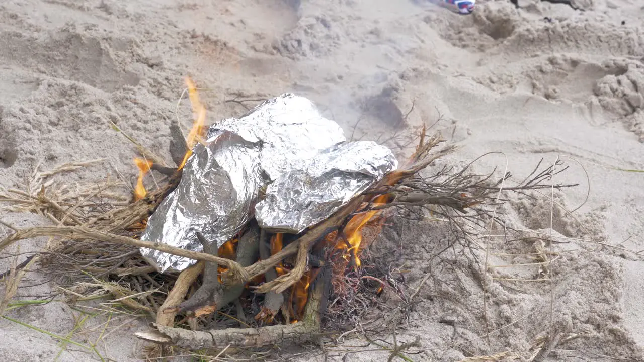 Fish wrapped in foil cooking on a fire on the beach