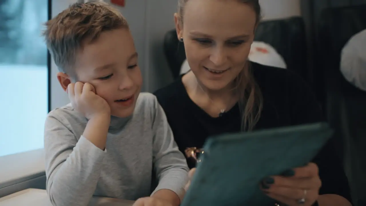 Mom and son playing on pad in train