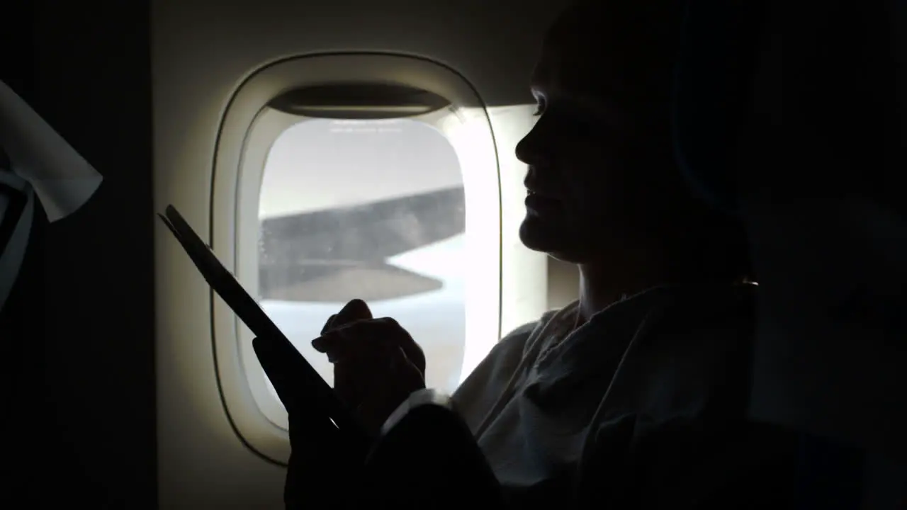 Woman sitting by illuminator in plane with touch pad