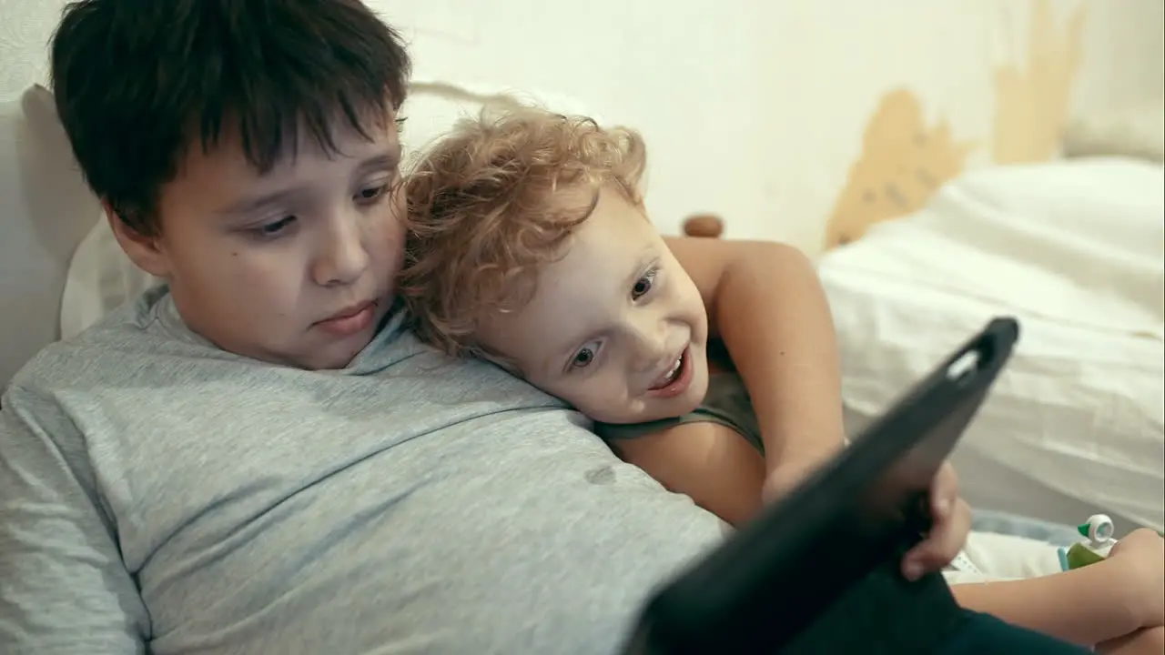 Two brothers with pad lying in bed Entertainment tablet PC