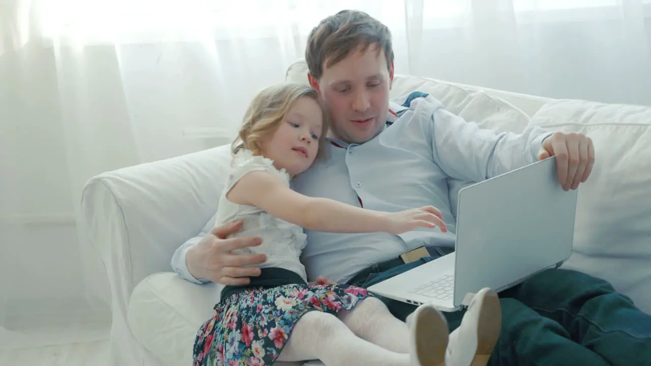 Father and daughter using laptop on the sofa