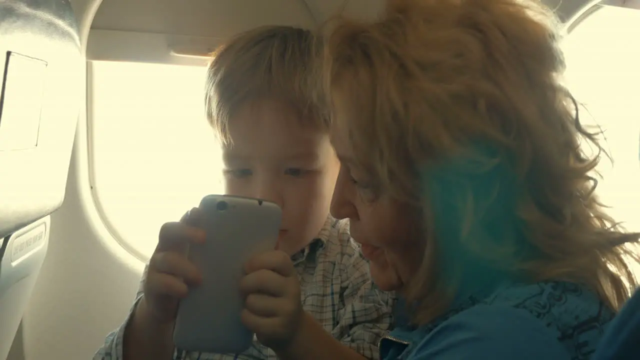 Child and grandmother entertaining with phone in plane