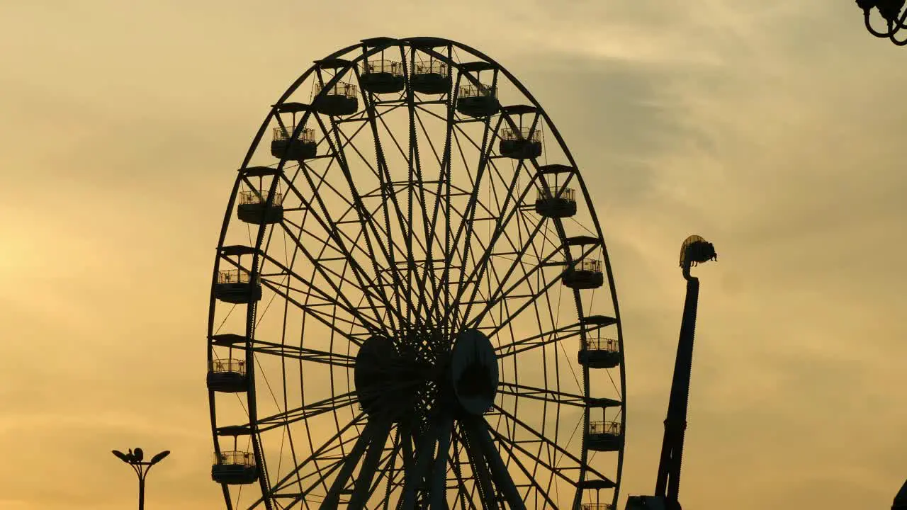 Ferris Wheel Silhouette Against Orange Sunset Sky