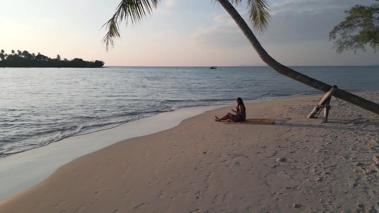 Woman doing during sunset sport exercise under palm trees on paradise beach