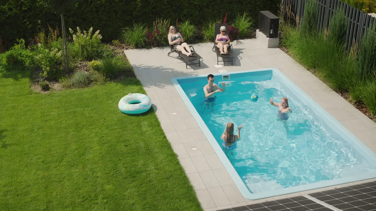 A cheerful family relaxes in the pool in the backyard of a villa Hot summer day