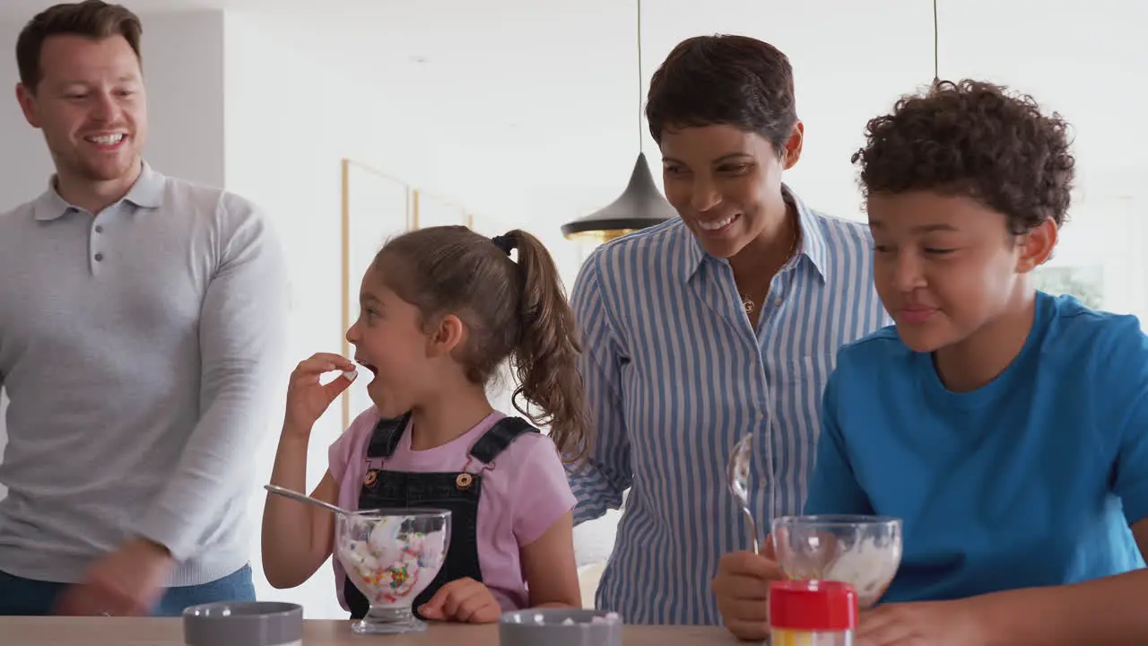 Parents Catch Children In Kitchen At Home Eating Ice Cream