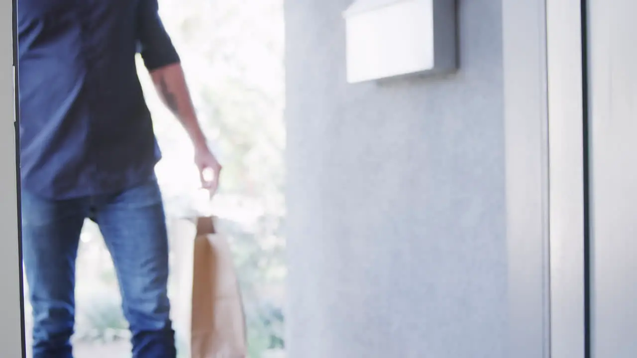 Close Up Of Home Delivery Service Driver Handing Takeaway Food Bags To Female Customer At Front Door