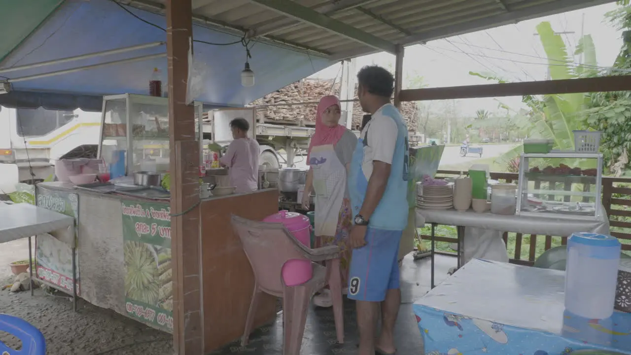 Southeast asian man stands and orders food at restaurant on Thai Malay border