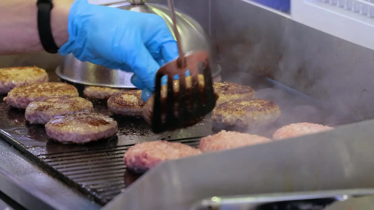 Meat beef patty is cooked in a hot frying pan Street food chef flips burgers with a spatula