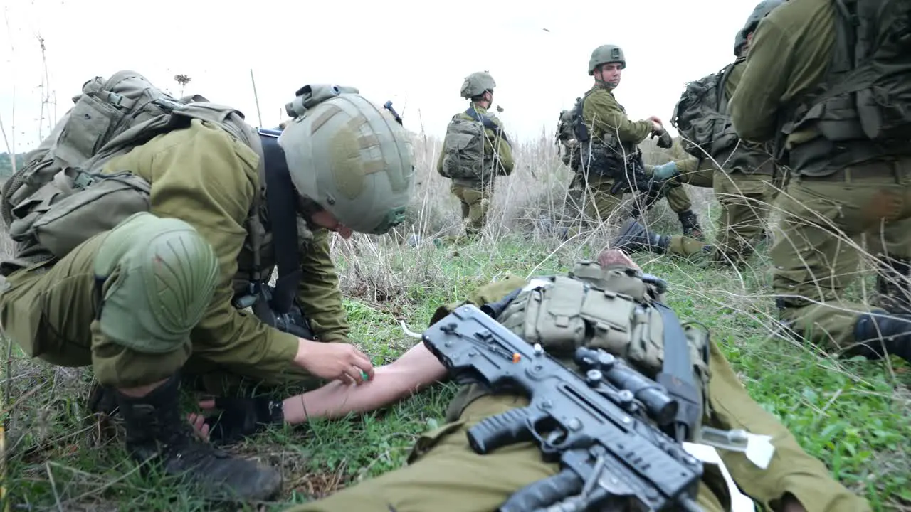 IDF combat medic give first aid to wounded infantry soldier dolly in