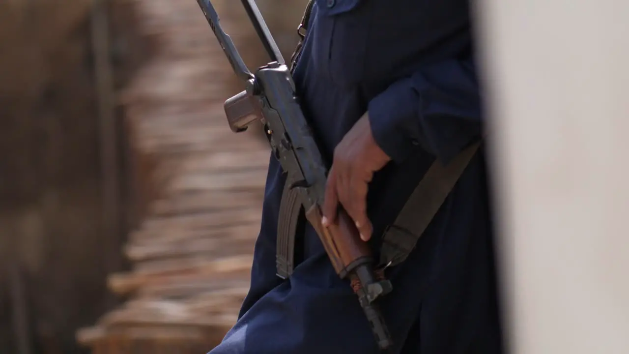 Lower Half View Of Male Leaning Against Wall Holding Kalashnikov Rifle