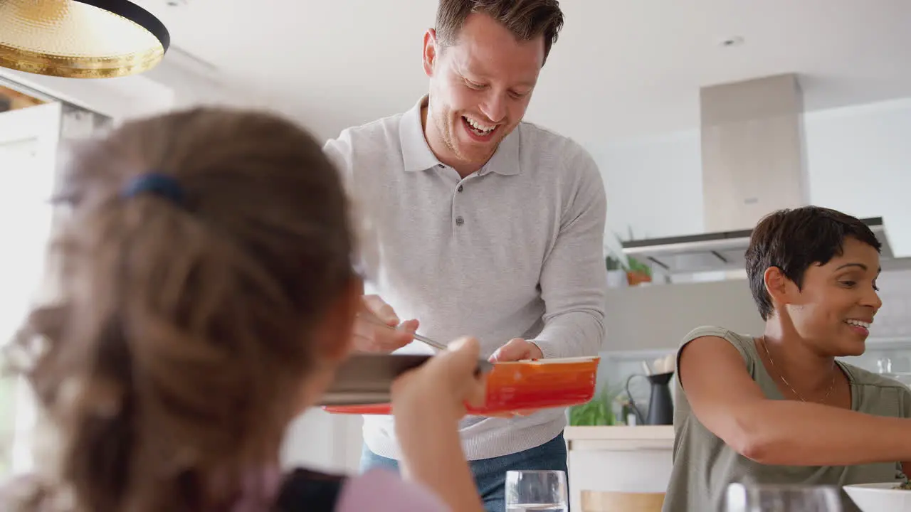 Multi-Generation Mixed Race Family Eating Meal Around Table At Home Together