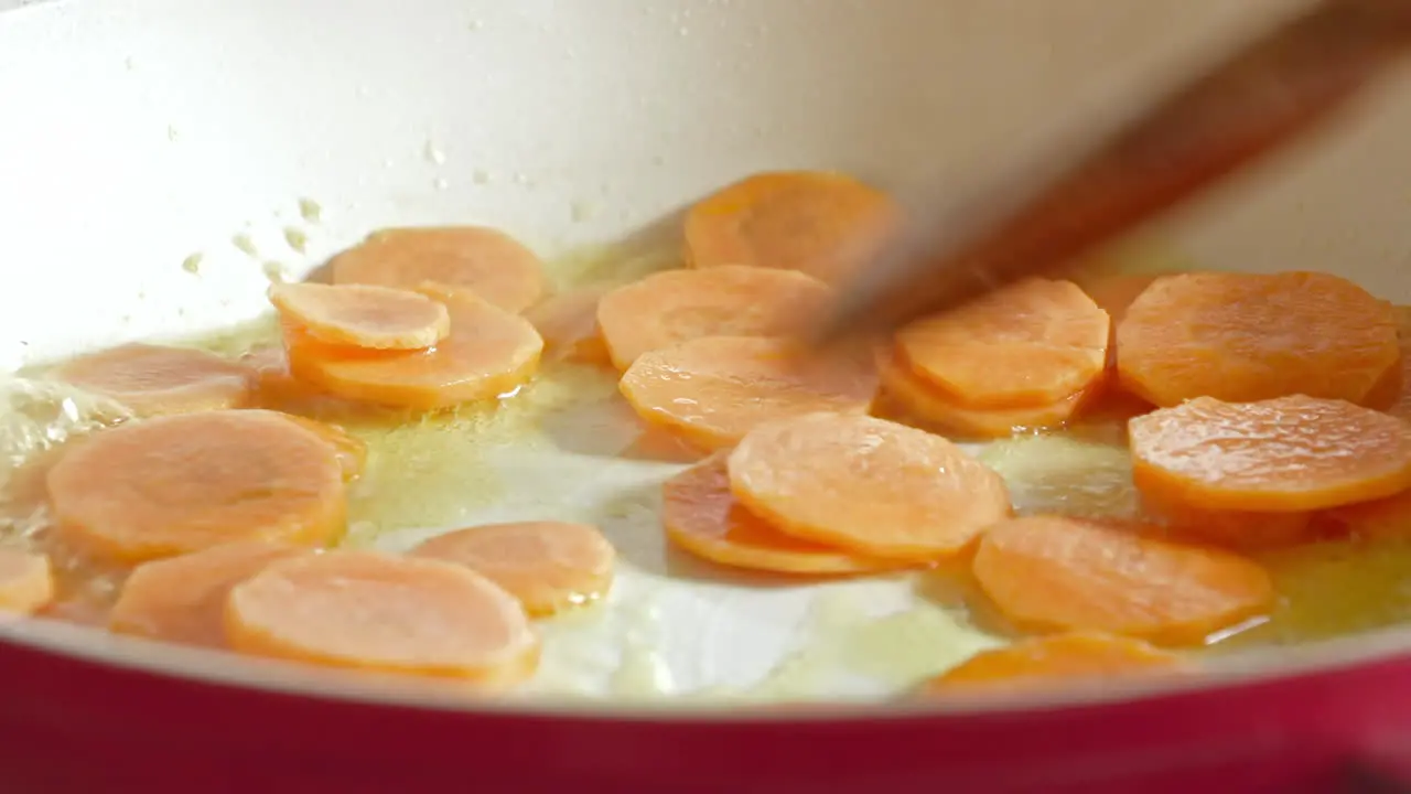 A close up of frying carrots in a pan