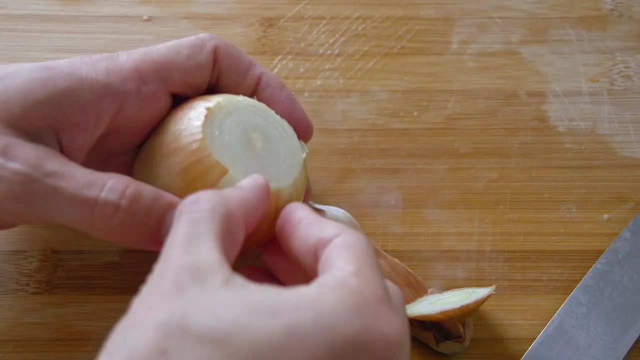 A close up of peeling an onion with a knife