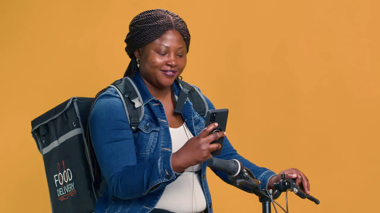 Woman Checks Cell Phone While On Bicycle