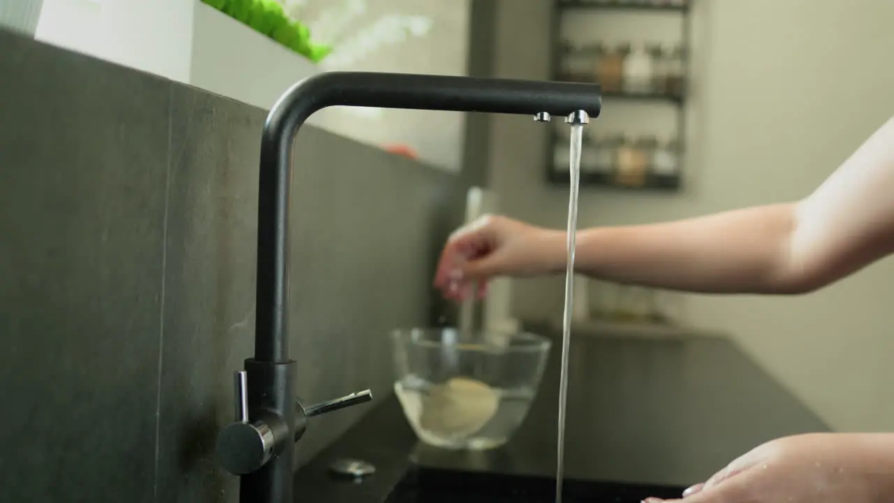 A housewife peels potatoes under running water Preparing food in her kitchen