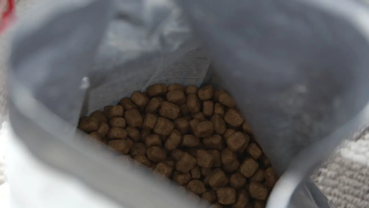 Close up of a hand entering a cat food bag and pulling out a large spoonful of food