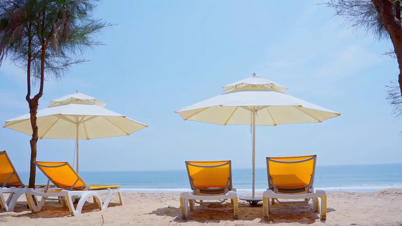 Natural sand beach and sea wave with yellow beach bench under white parasol umbrella on tropical island beach